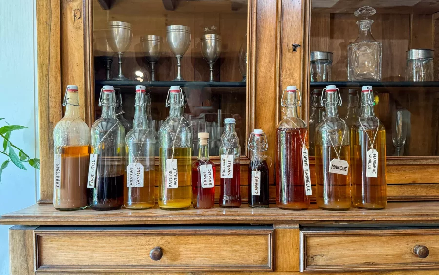 Bouteilles sur un meuble en bois de la ferme à Foncine – Arrière-Cour, agence spécialisée dans le Jura