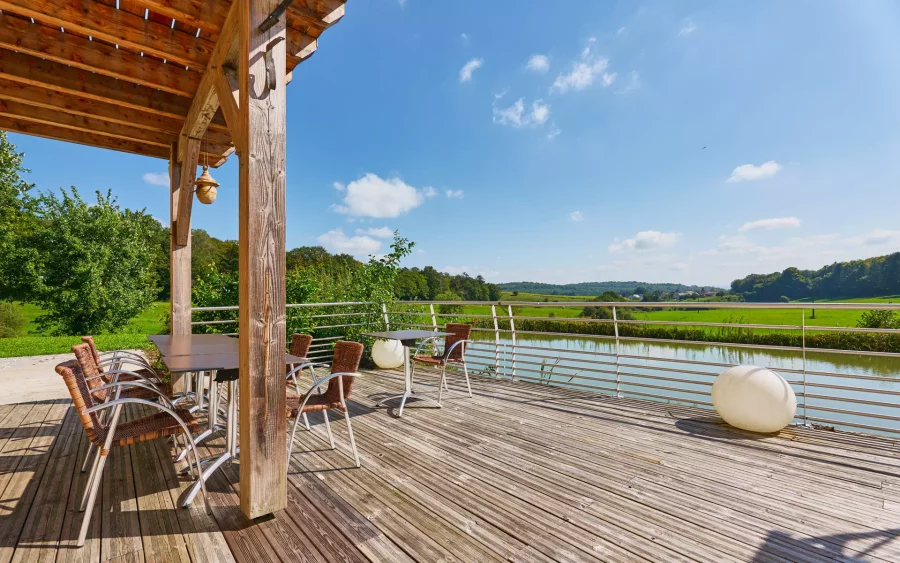 Vue de la terrasse en bois de la ferme rénovée avec terres agricoles BIO à vendre proche de Montbéliard – Arrière-Cour, agence immobilière spécialisée à Montbéliard