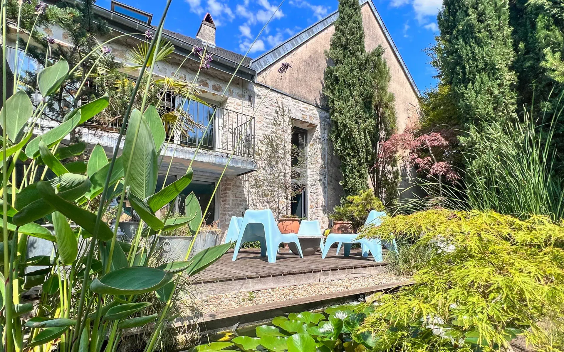 Verdure et sièges sur la terrasse ensoleillée de l’Appartement avec piscine situé à Besançon – Arrière-Cour, agence immobilière spécialisée à Besançon