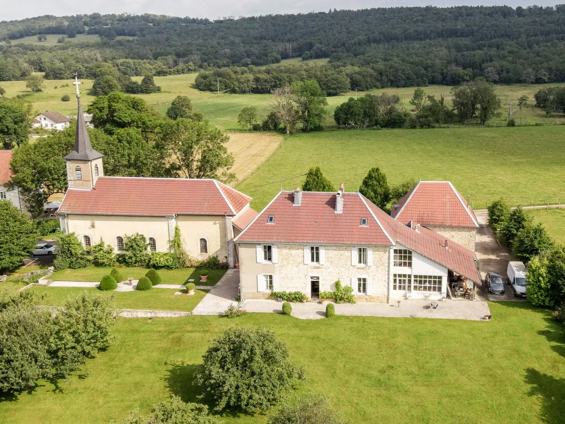 Vue drone de la façade en pierres de l'Ancien Presbytère dans le Doubs - Arrière-Cour, agence immobilière spécialisée dans le Doubs