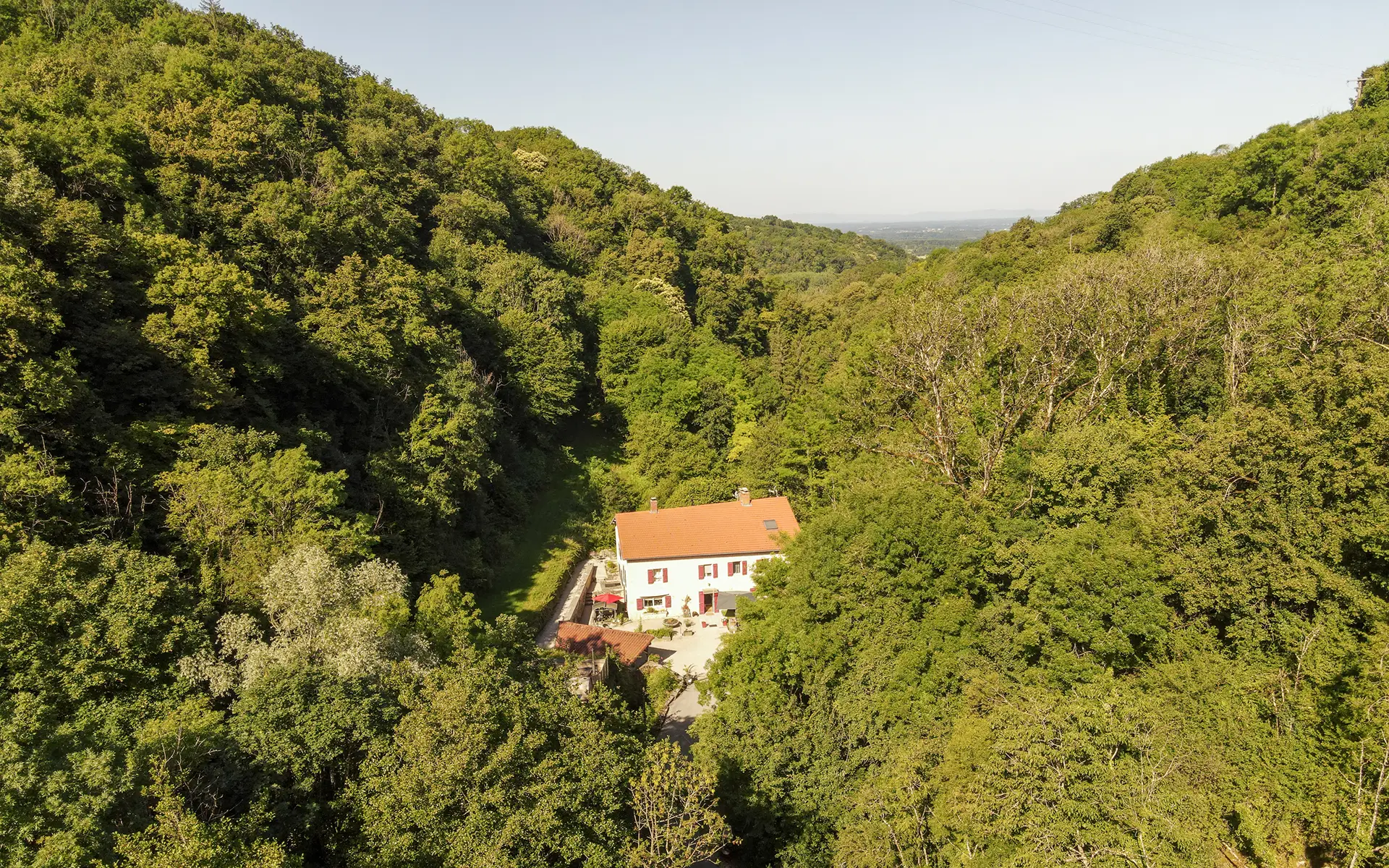 Nature et la façade d'un ancien moulin restauré à Saint-Amour à vendre - Arrière-Cour, agence immobilière spécialisée dans le Jura
