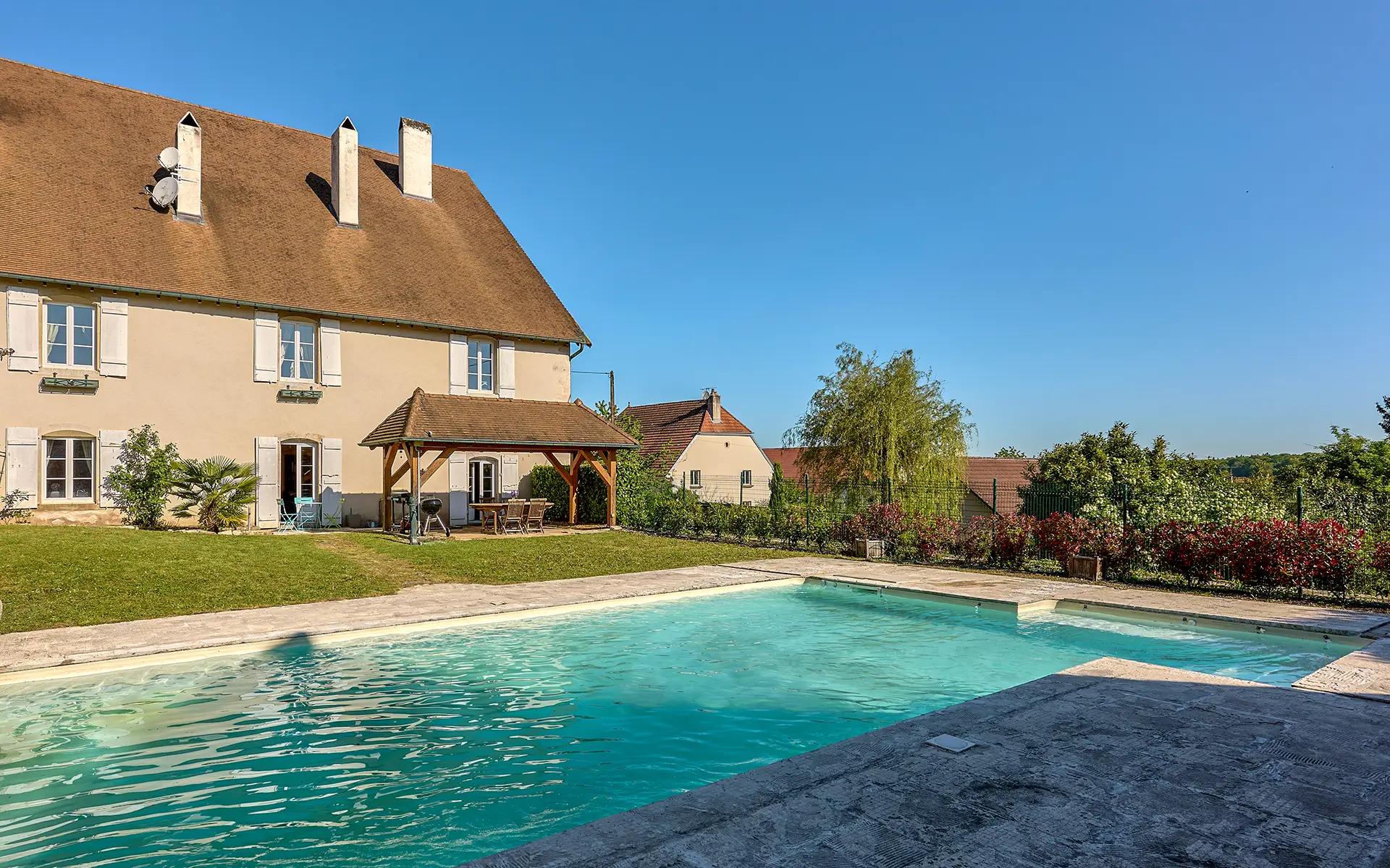 Façade et piscine de l'ancien relais de poste proche de Besançon à vendre - Arrière-Cour, agence immobilière spécialisée à Besançon