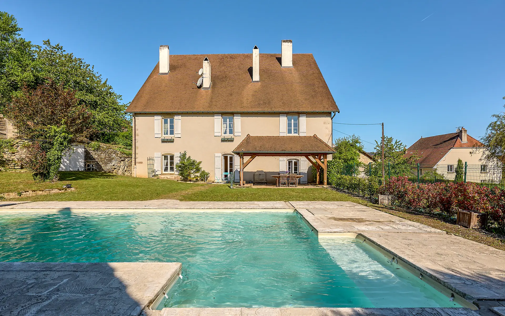 Façade lumineuse et piscine de l'ancien relais de poste proche de Besançon à vendre - Arrière-Cour, agence immobilière spécialisée à Besançon