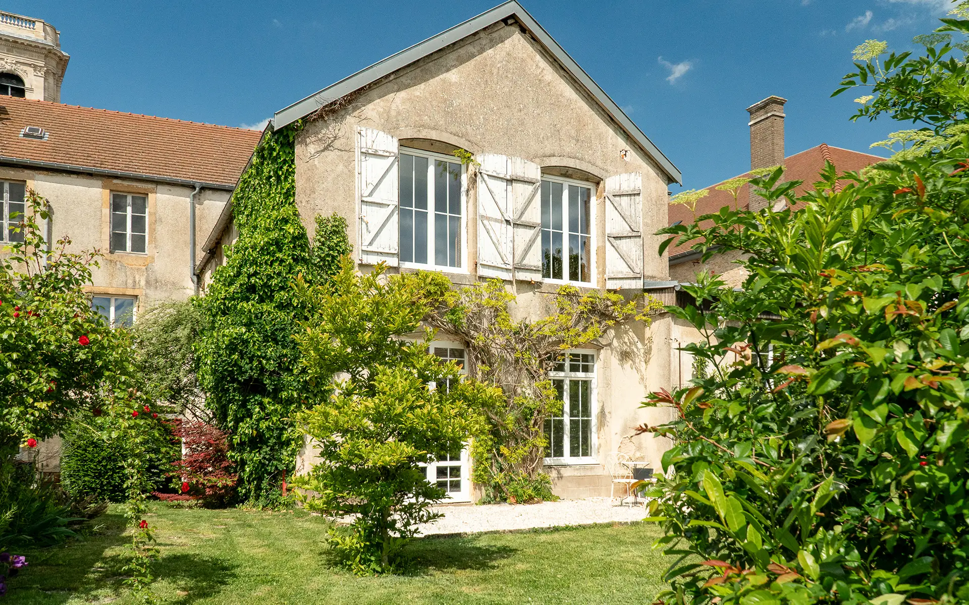 Verdure et la façade de la maison de caractère à Langres à vendre - Arrière-Cour, agence immobilière spécialisée en Haute-Marne