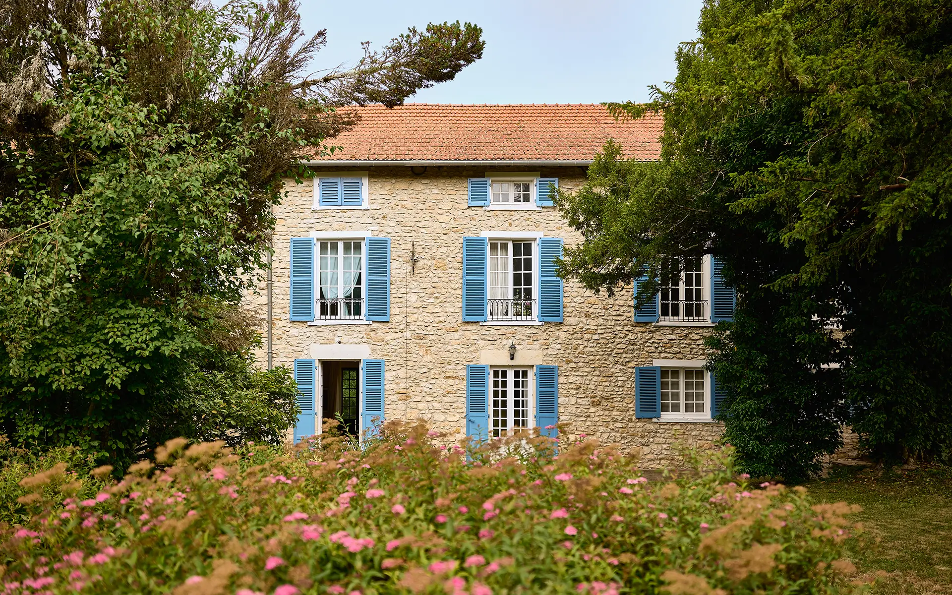 Façade fleurie de la maison ancienne à Igny à vendre - Arrière-Cour, agence immobilière spécialisée en Haute-Saône