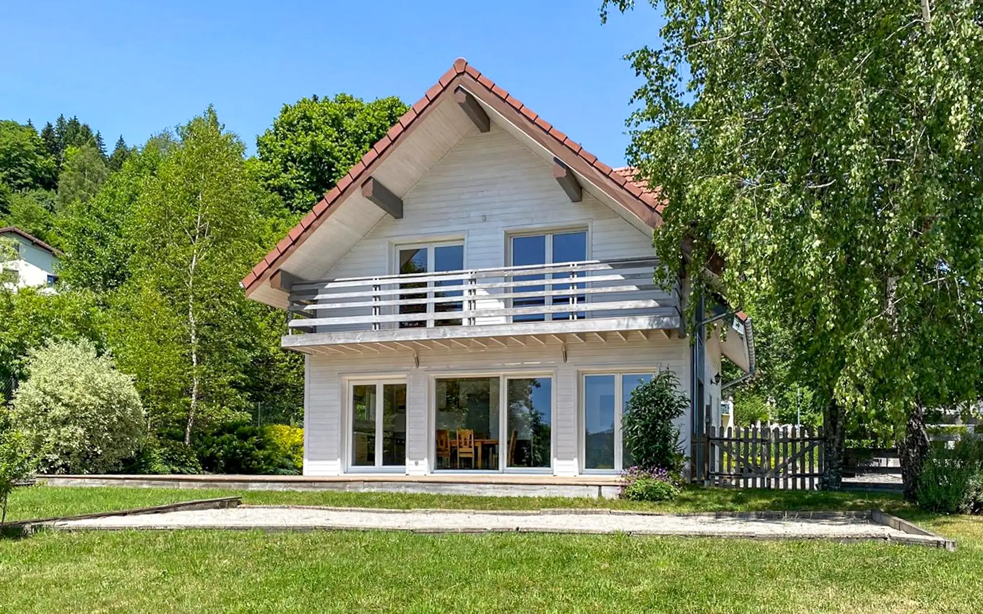 Verdure et façade du chalet moderne avec spa au coeur des Hautes-Vosges à vendre - Arrière-Cour, agence immobilière spécialisée en Mayenne