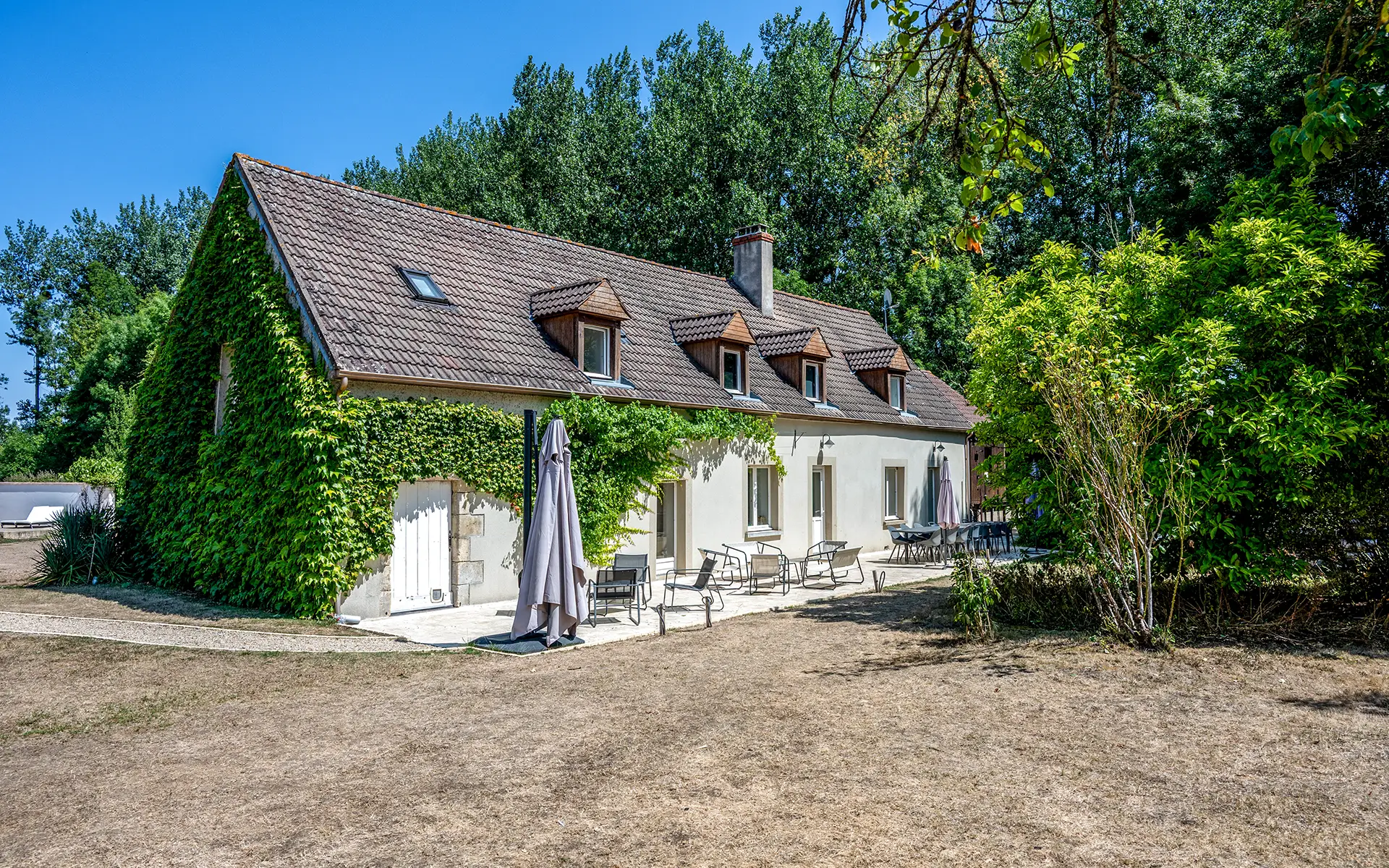 Façade et terrasse du moulin proche de Sancerre à vendre - Arrière-Cour, agence immobilière spécialisée dans le Cher