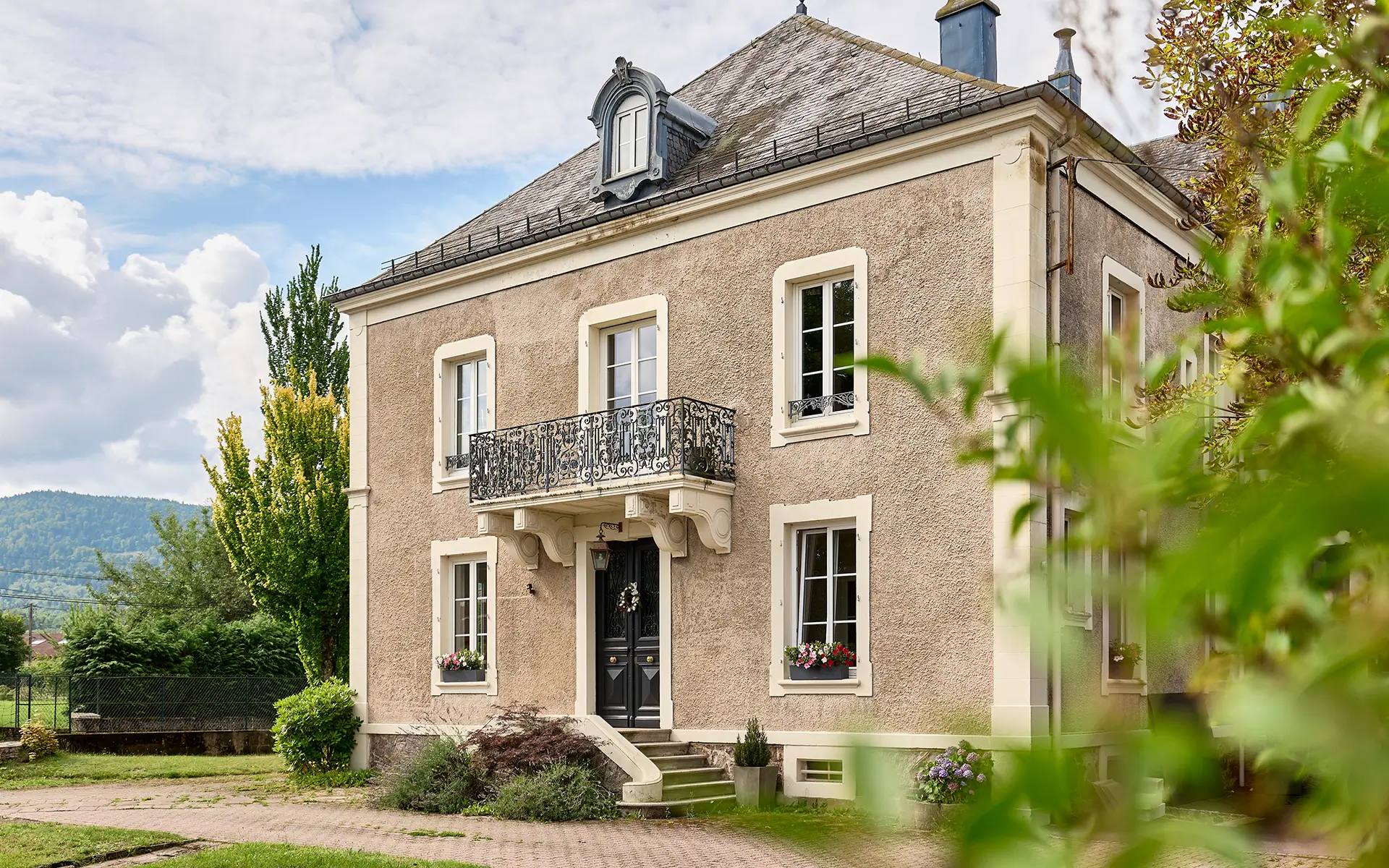 Façade lumineuse de la demeure familiale avec jardin en coeur de ville vosgien à vendre - Arrière-Cour, agence immobilière spécialisée en Haute-Saône