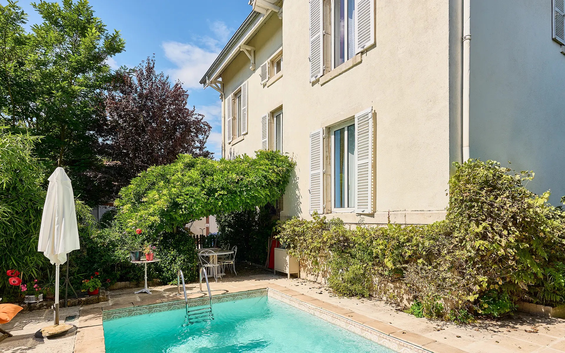 Façade et piscine de la maison en pierre proche de Dole à vendre - Arrière-Cour, agence immobilière spécialisée dans le Doubs