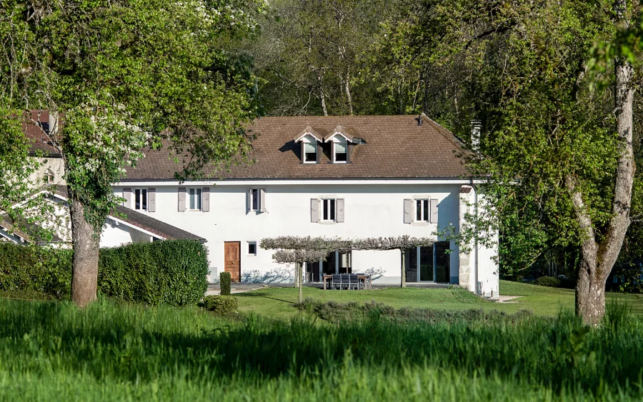 Verdure et façade de l'ancienne ferme rénovée à Divonne-les-Bains dans le Pays de Gex à vendre - Arrière-Cour, agence immobilière spécialisée dans le Pays de Gex