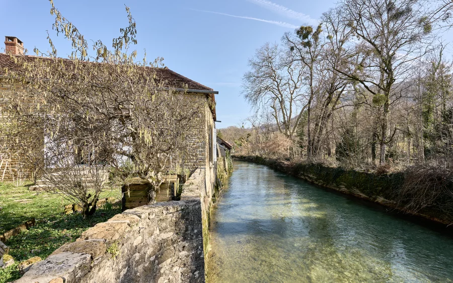 Façade lumineuse de la maison en pierre à Voiteur au bord de la Seille à vendre - Arrière-Cour, agence immobilière spécialisée dans le Jura