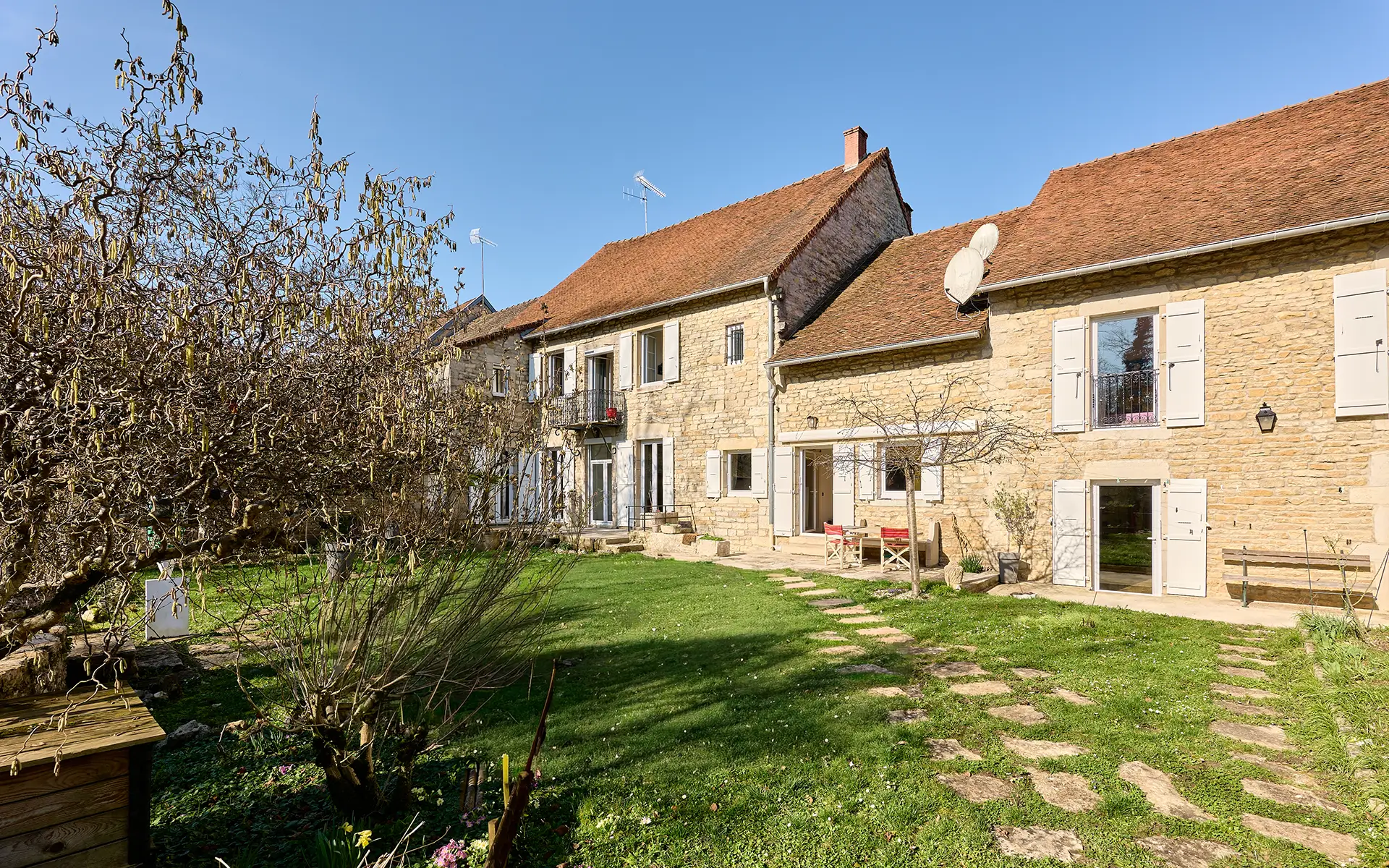 Façade et jardin de la maison en pierre à Voiteur au bord de la Seille à vendre - Arrière-Cour, agence immobilière spécialisée dans le Jura