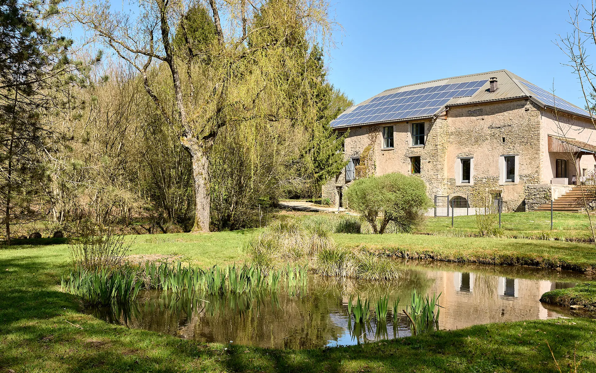 Façade et étang du moulin XVIIIe siècle rénové, à Rioz à vendre - Arrière-Cour, agence immobilière spécialisée en Haute-Saône