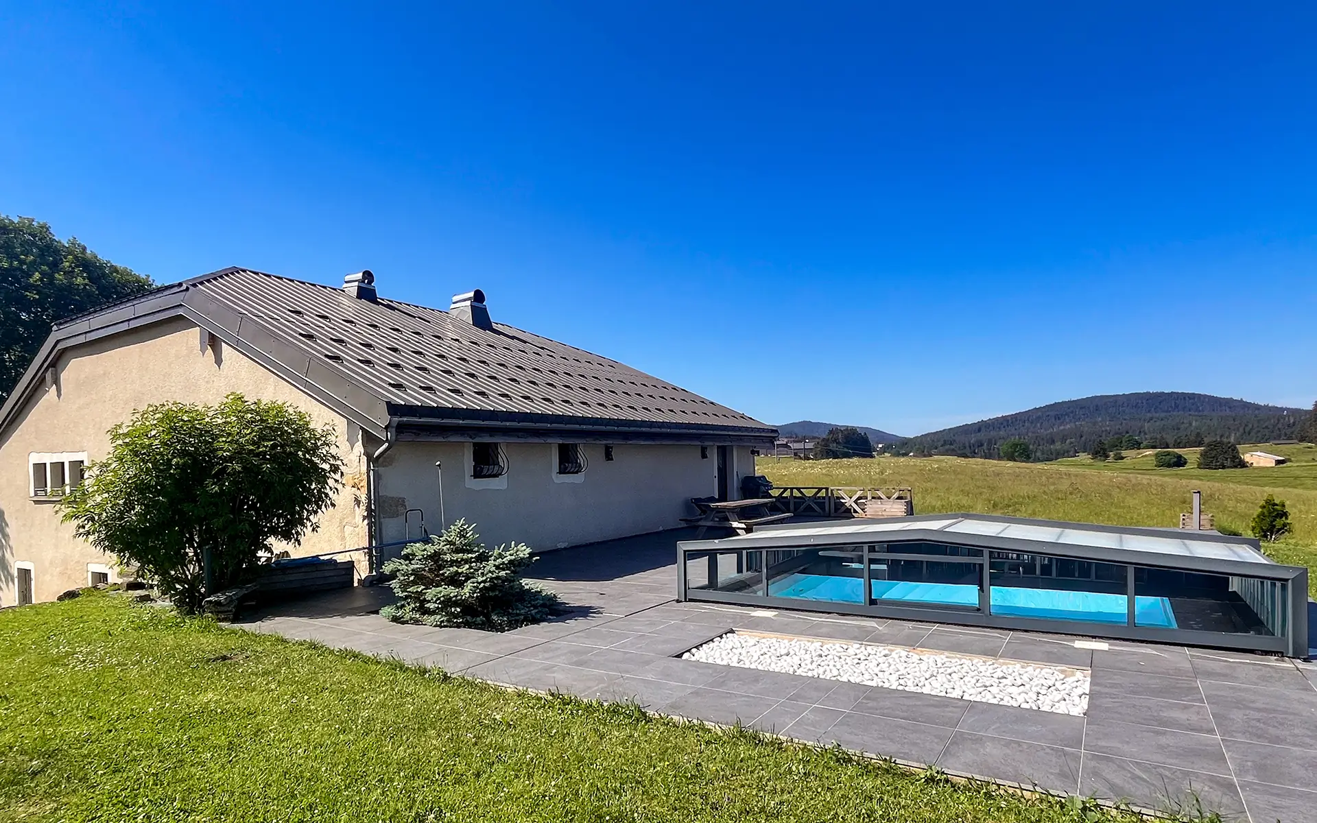 Façade et piscine de la ferme rénovée aux Rousses dans le Jura à vendre - Arrière-Cour, agence immobilière spécialisée dans le Jura