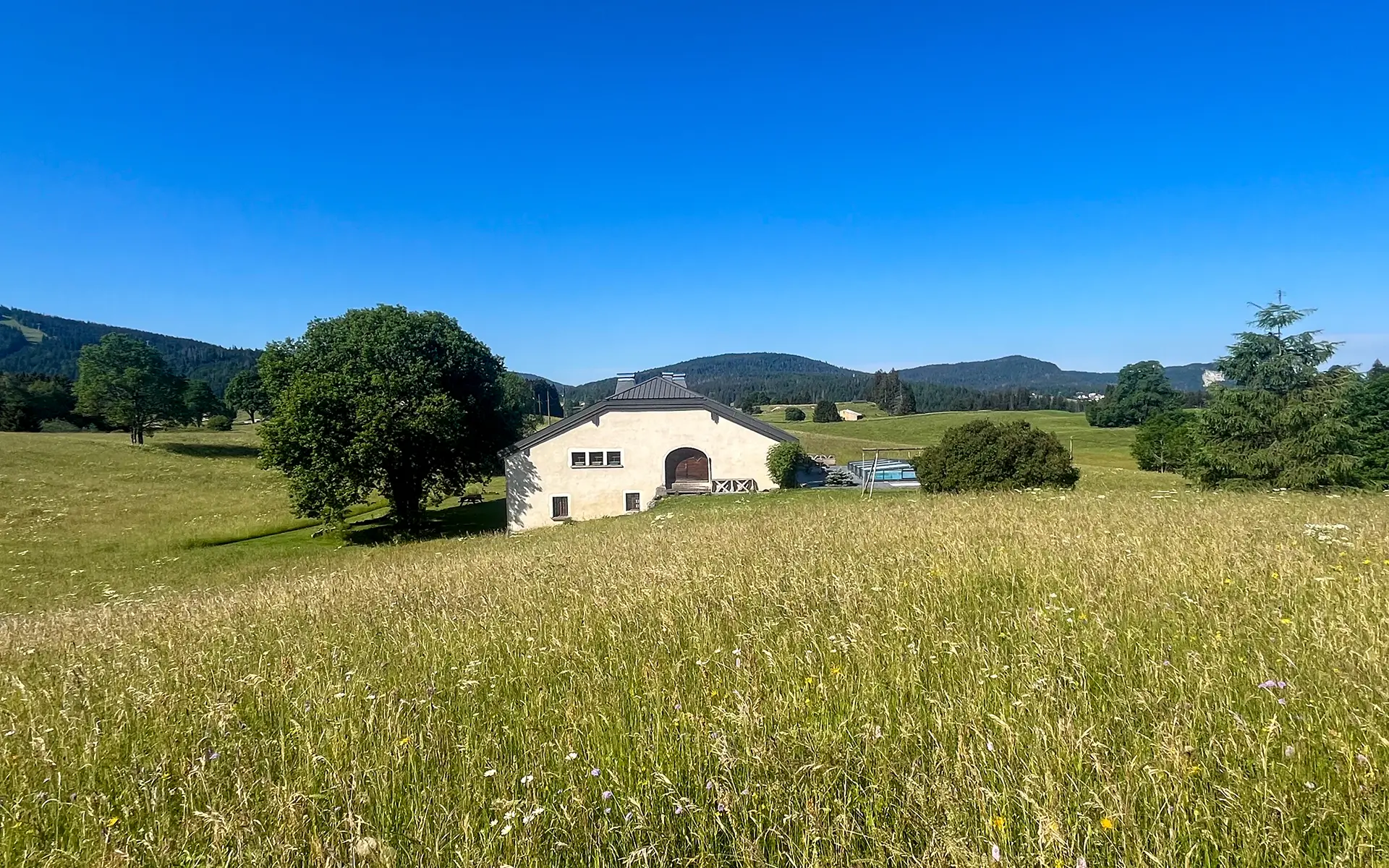 Façade et verdure de la ferme rénovée aux Rousses dans le Jura à vendre - Arrière-Cour, agence immobilière spécialisée dans le Jura