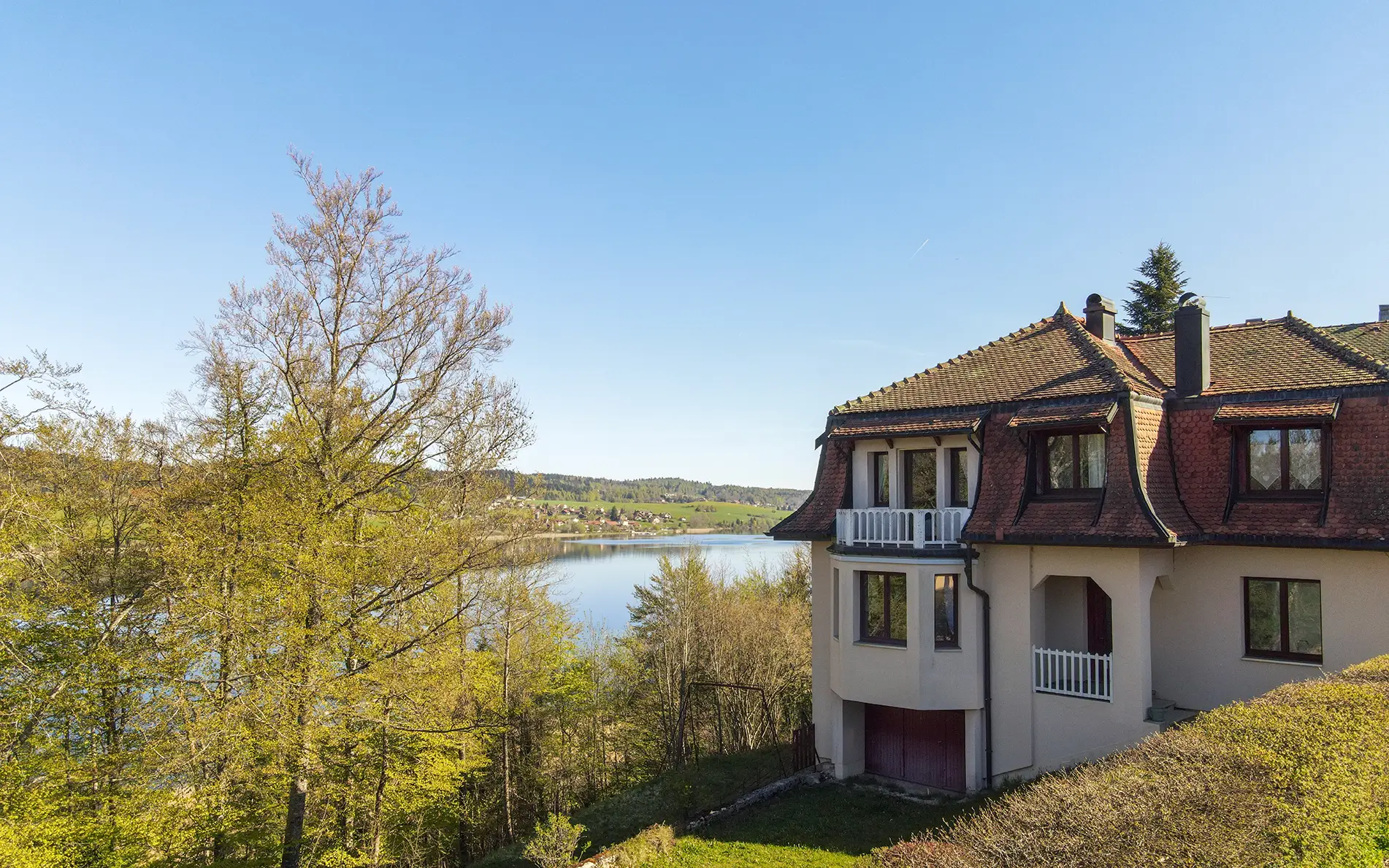 Jardin et facade de la maison des années 30 à Malbuisson avec vue lac à vendre - Arrière-Cour, agence immobilière spécialisée dans le Doubs