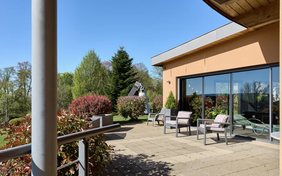 Terrasse et verdure de la villa contemporaine sur les hauteurs des Montboucons à vendre - Arrière-Cour, agence immobilière spécialisée dans le Doubs