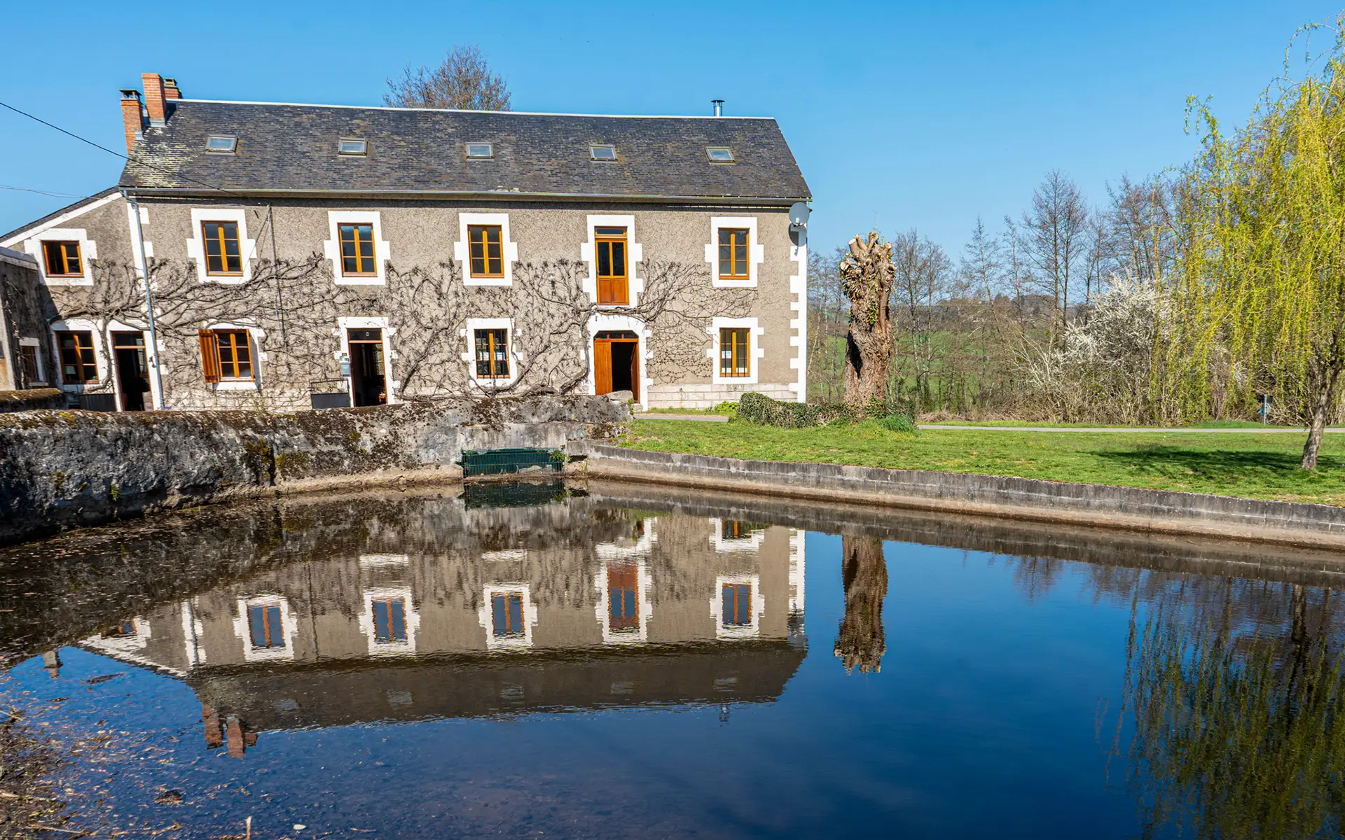 Façade et étang du moulin de Vaupranges dans le Morvan à vendre - Arrière-Cour, agence immobilière spécialisée dans le Morvan
