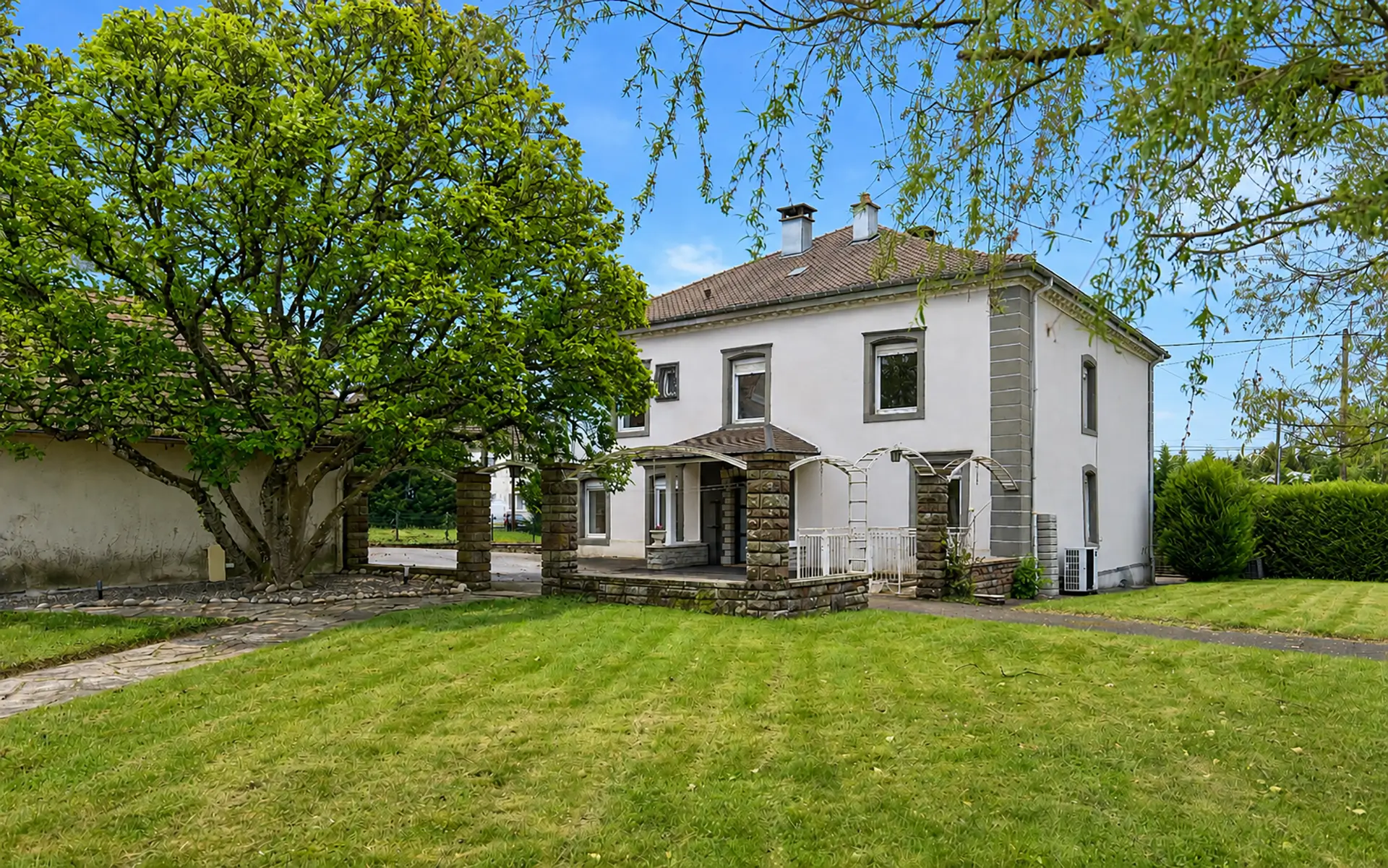 Façade et jardin de la maison de maître rénovée à Roppe à vendre - Arrière-Cour, agence immobilière spécialisée dans le Territoire de Belfort