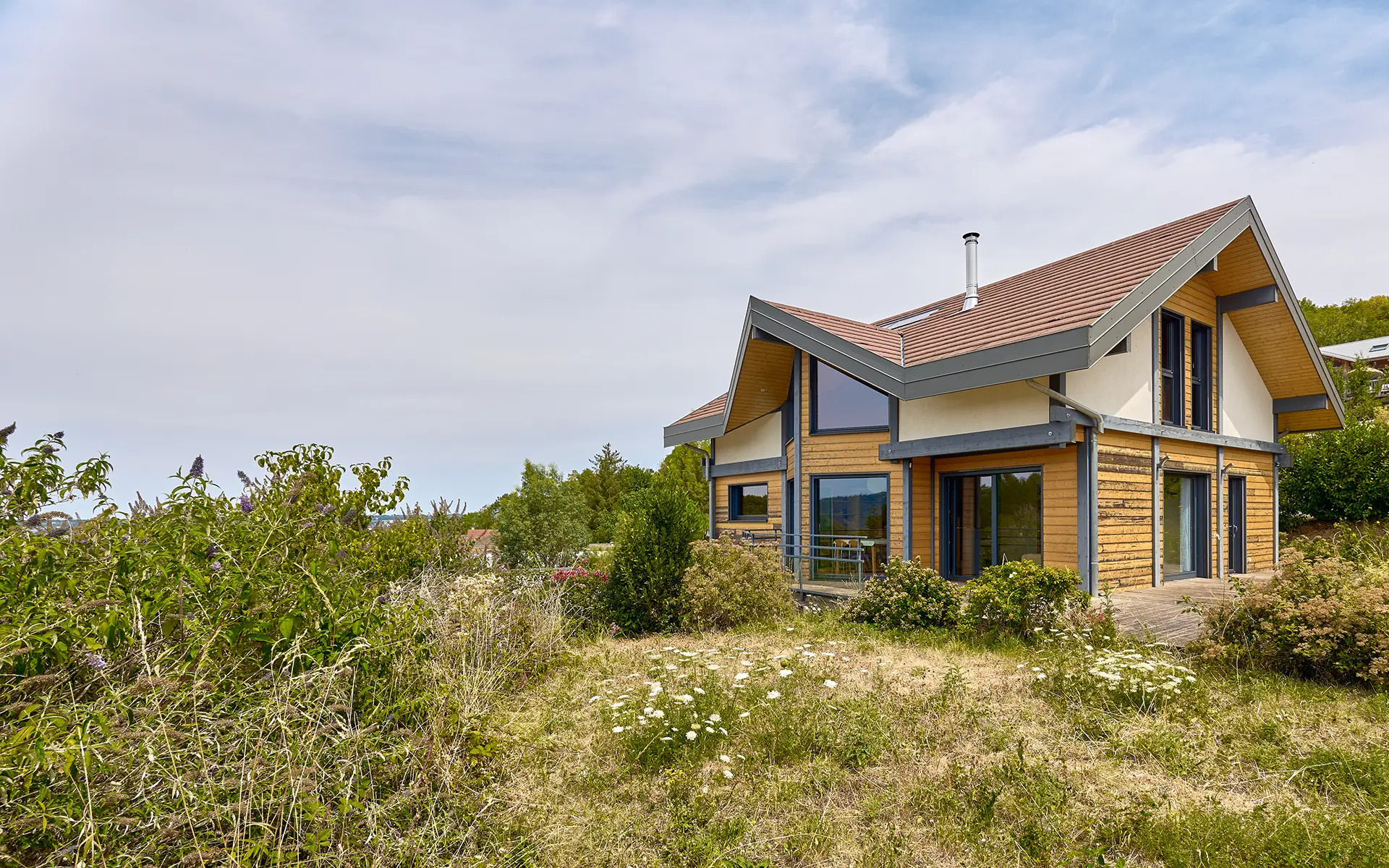 Façade et verdure de la maison contemporaine sur les hauteurs de Besançon à vendre - Arrière-Cour, agence immobilière spécialisée dans le Doubs
