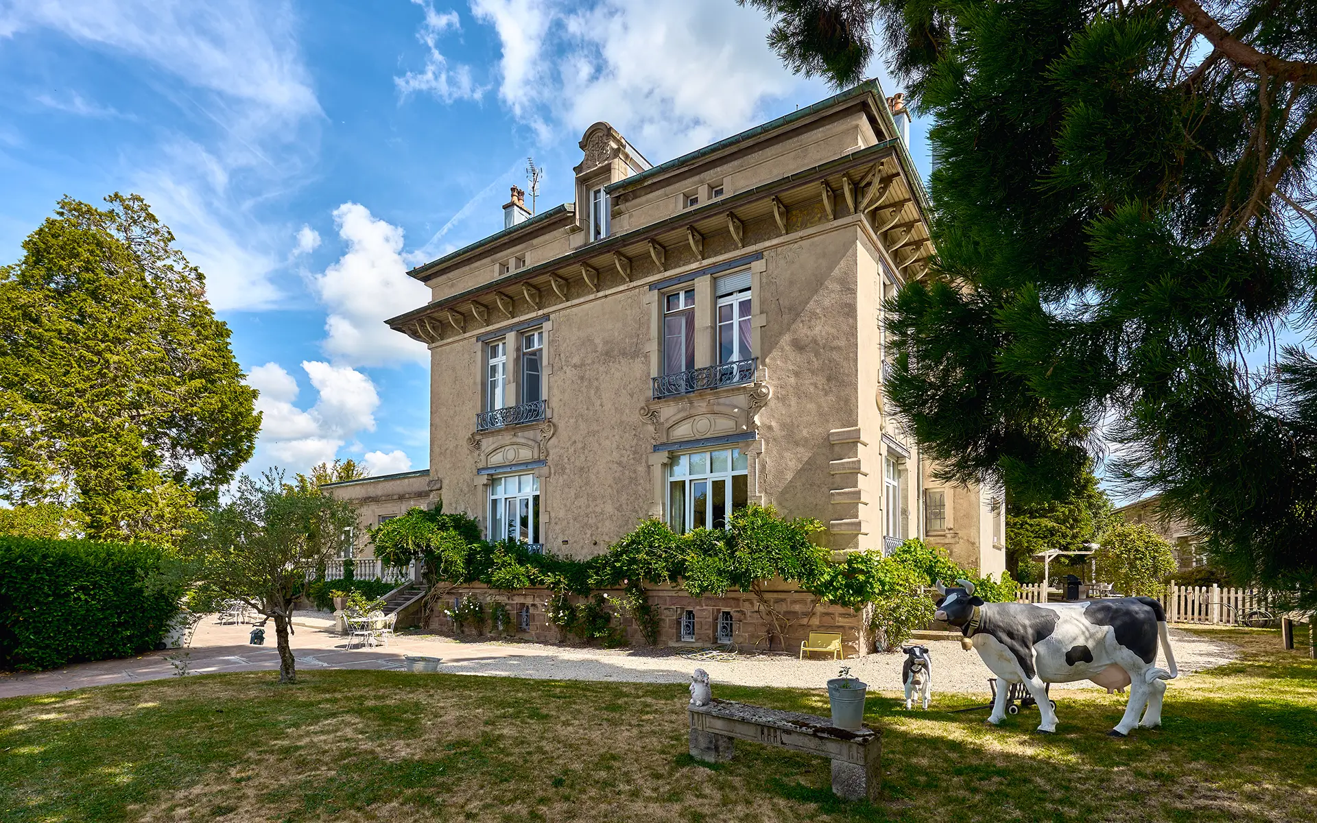Façade et verdure d'une demeure de caractère à Luxeuil-les-Bains à vendre - Arrière-Cour, agence immobilière spécialisée en Haute-Saône