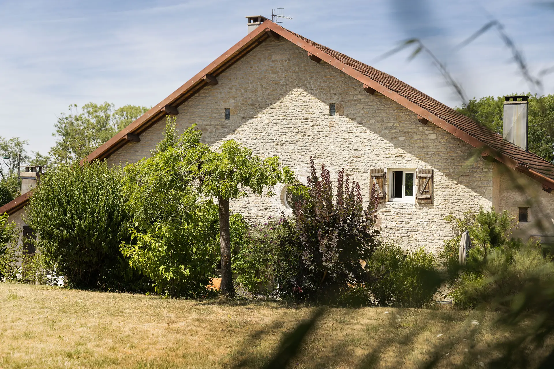 Façade et jardin de l'ancienne ferme rénovée aux portes d'Ornans à vendre - Arrière-Cour, agence immobilière spécialisée dans le Doubs
