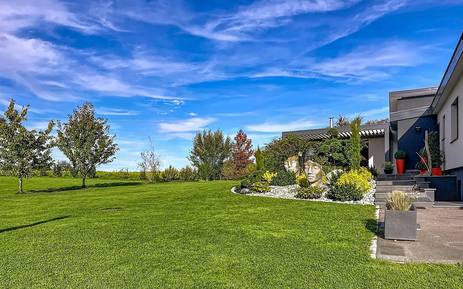Façade et verdure de la villa de plain-pied entre Belfort et la Suisse à vendre - Arrière-Cour, agence immobilière spécialisée dans le Territoire-de-Belfort
