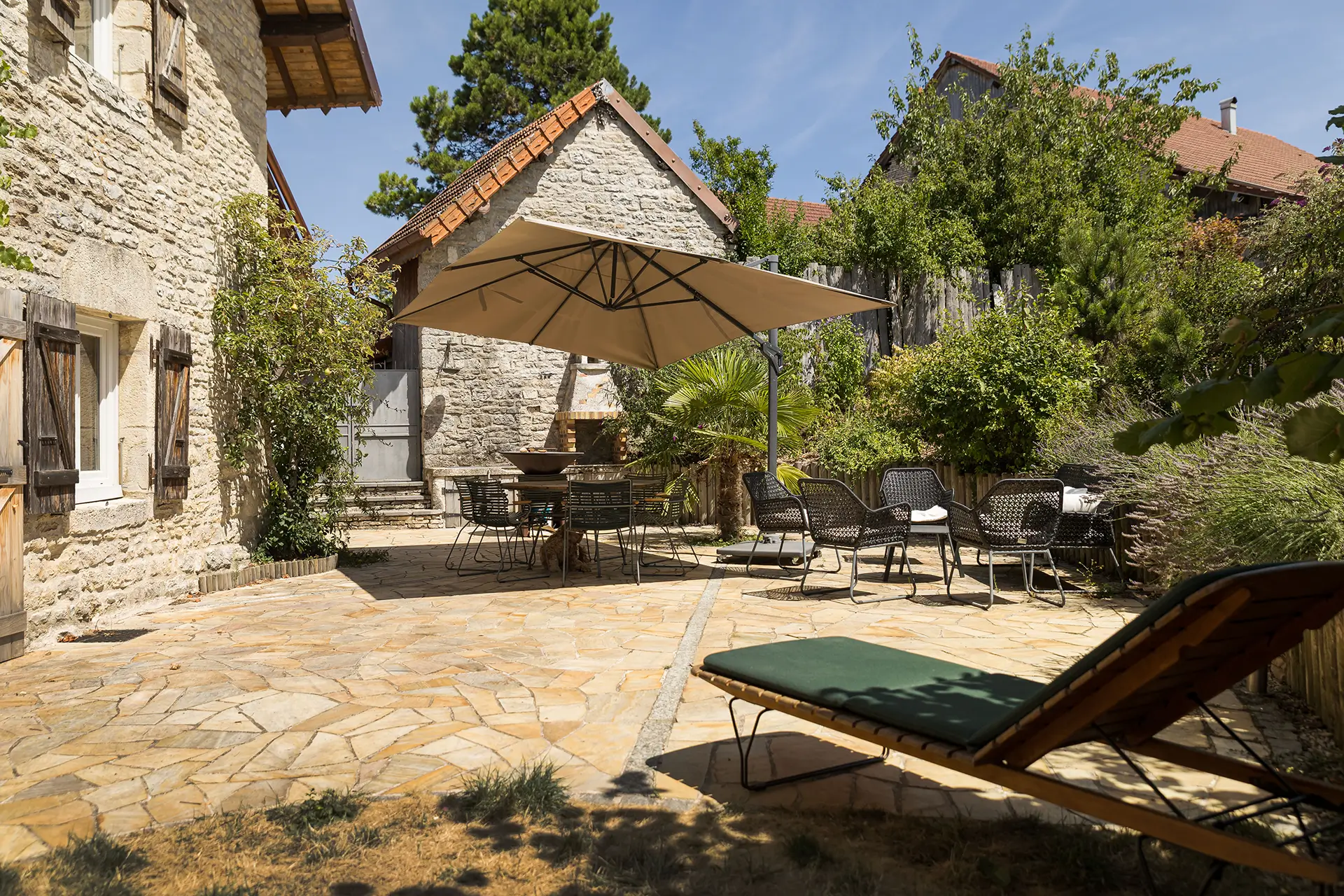 Terrasse et façade de l'ancienne ferme rénovée aux portes d'Ornans à vendre - Arrière-Cour, agence immobilière spécialisée dans le Doubs