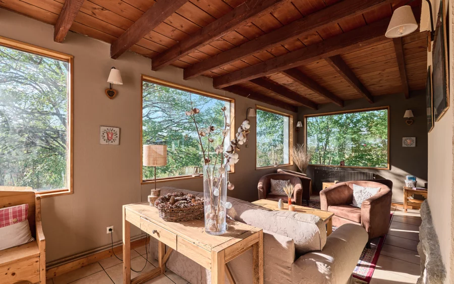 Salon cocon de l'hôtel ouvert sur les forêts du Jura à vendre - Arrière-Cour, agence immobilière spécialisée dans le Jura
