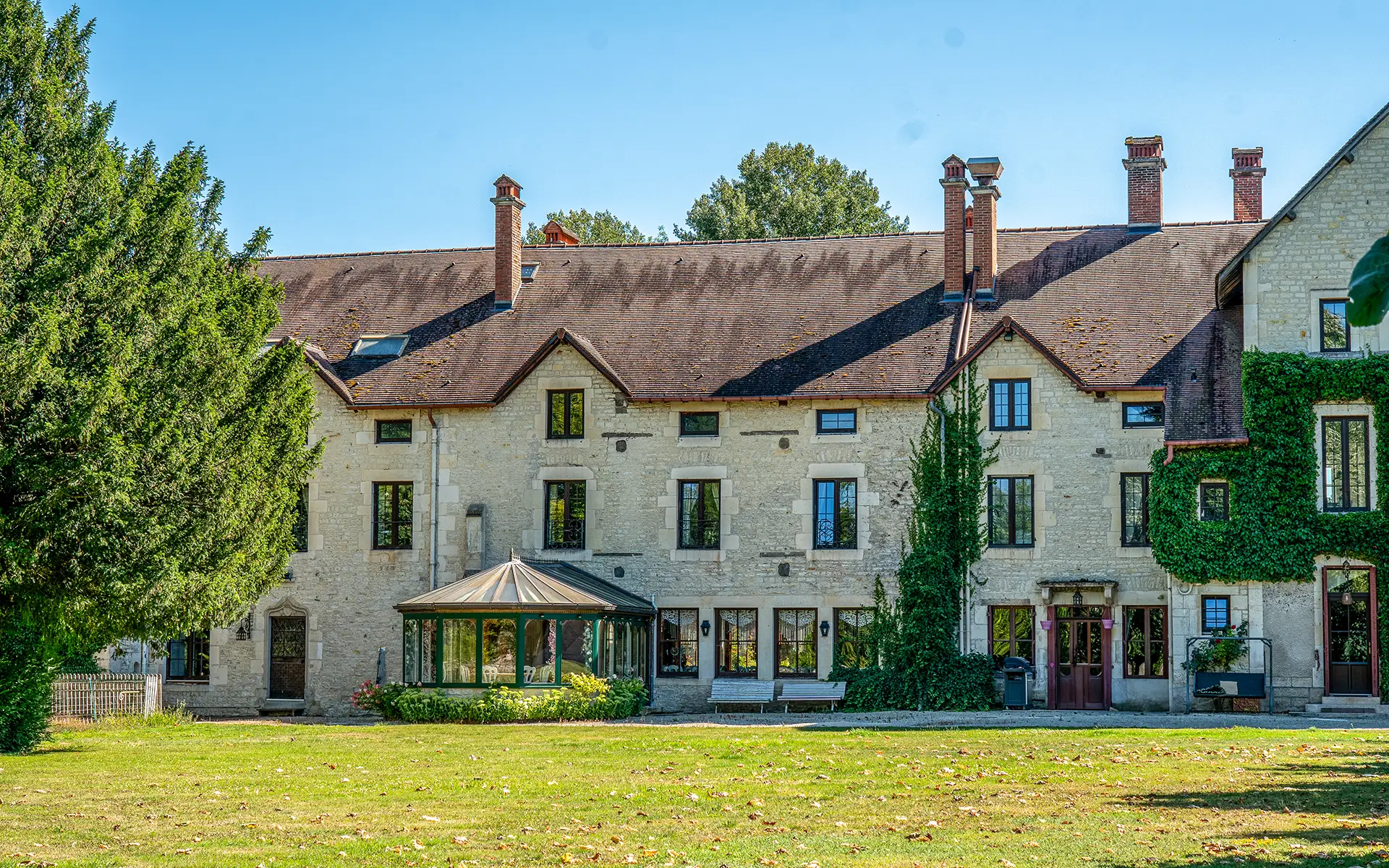 Façade d’un manoir ancien en pierre entouré d’un parc arboré