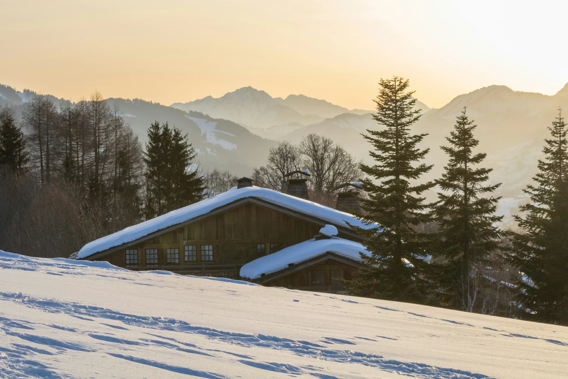 Chalet traditionnel sous la neige face aux montagnes de Savoie