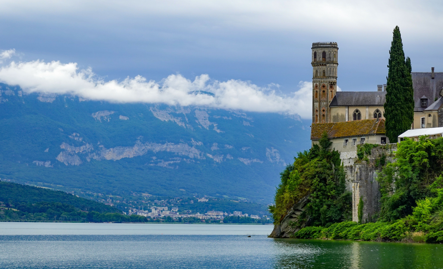 Lac bordé d’un édifice historique et de montagnes en Rhône-Alpes