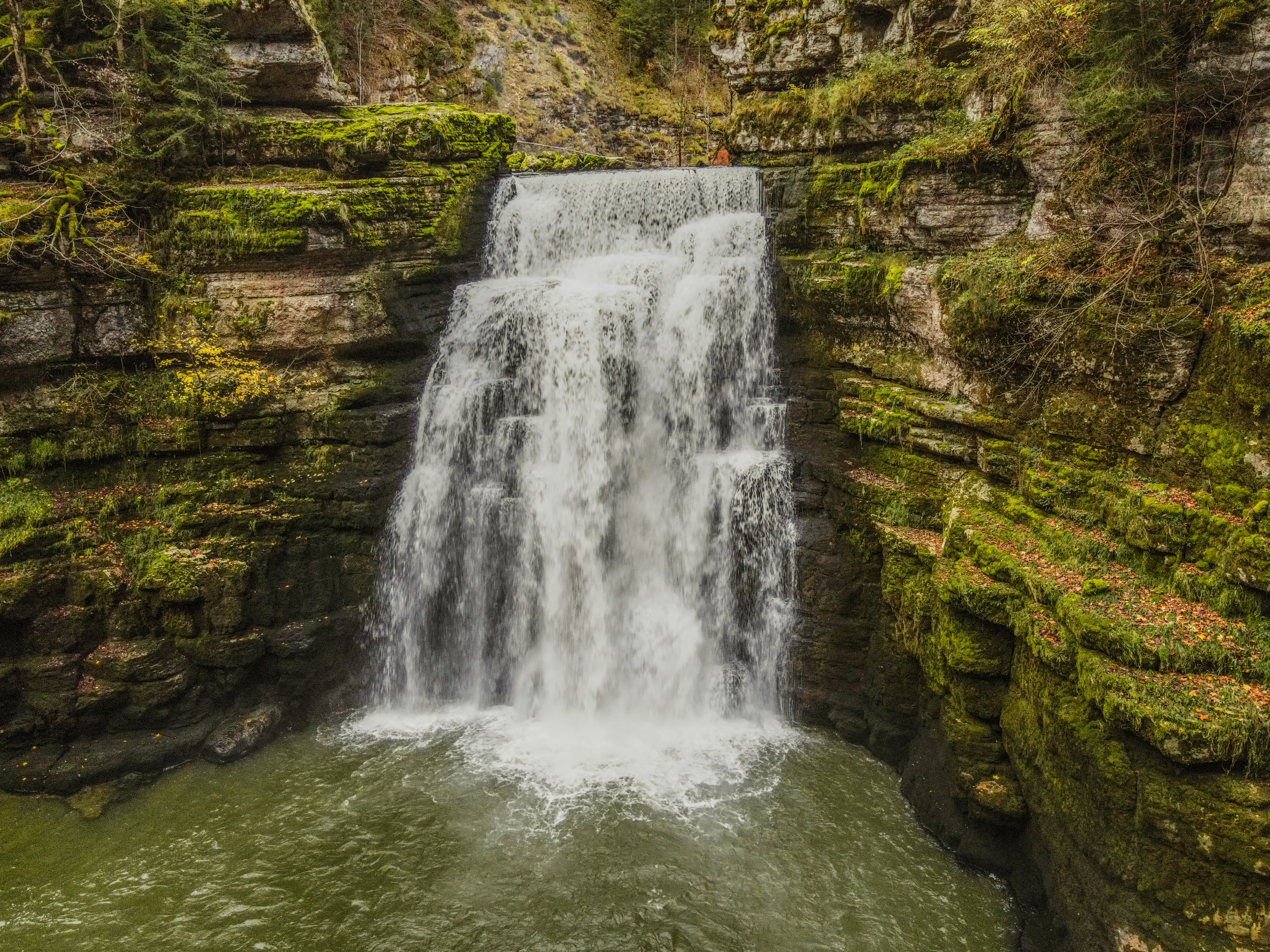 Cascade entourée de falaises et de forêt dans le Doubs