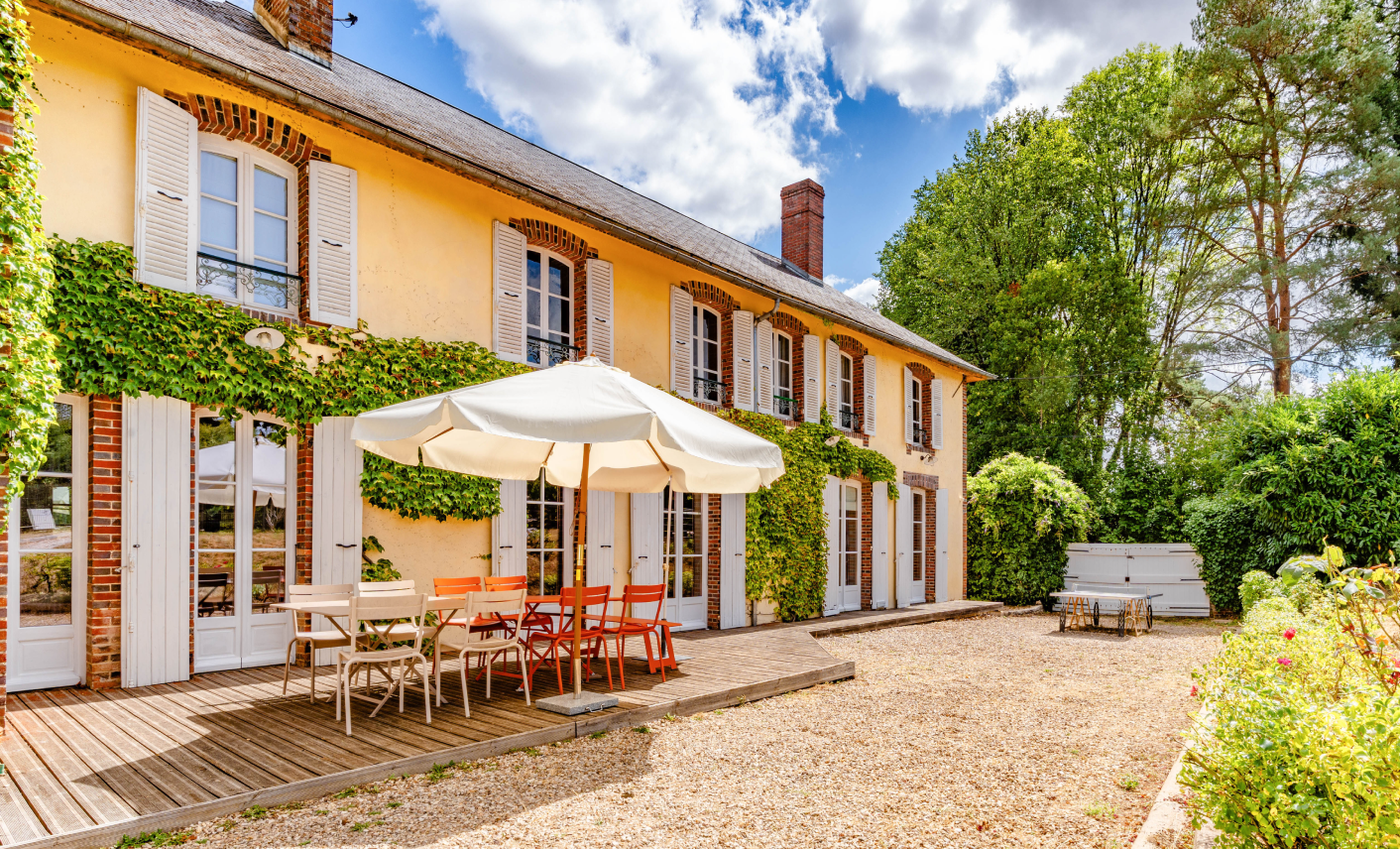 Demeure ancienne avec façade végétalisée et terrasse ouverte sur le jardin