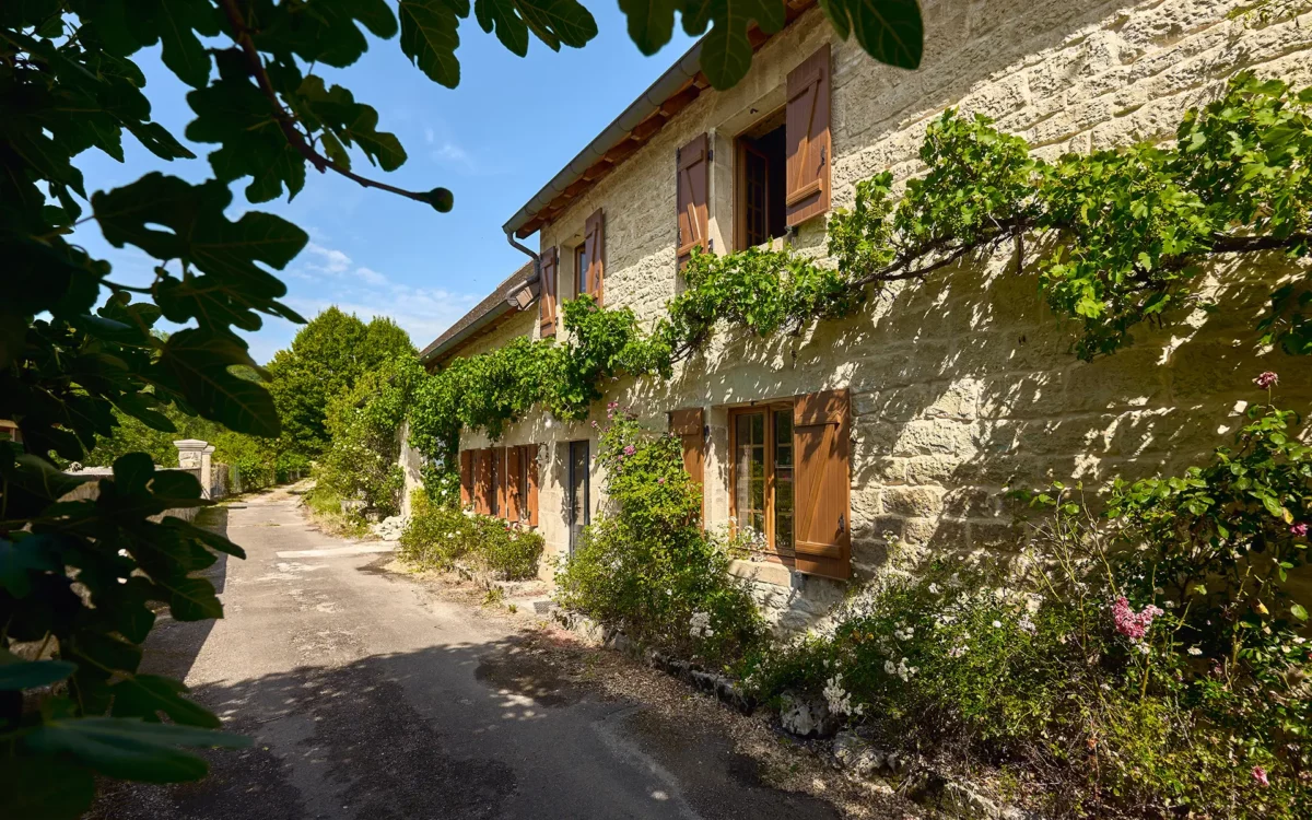 Façade lumineuse de la maison en pierre à Port-Lesney à vendre - Arrière-Cour, agence immobilière spécialisée dans le Jura