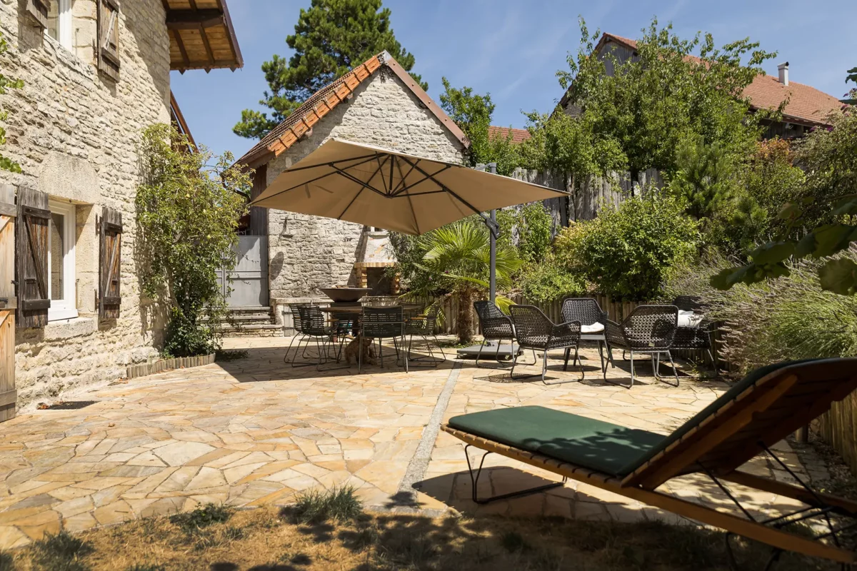 Terrasse et façade de l'ancienne ferme rénovée aux portes d'Ornans à vendre - Arrière-Cour, agence immobilière spécialisée dans le Doubs